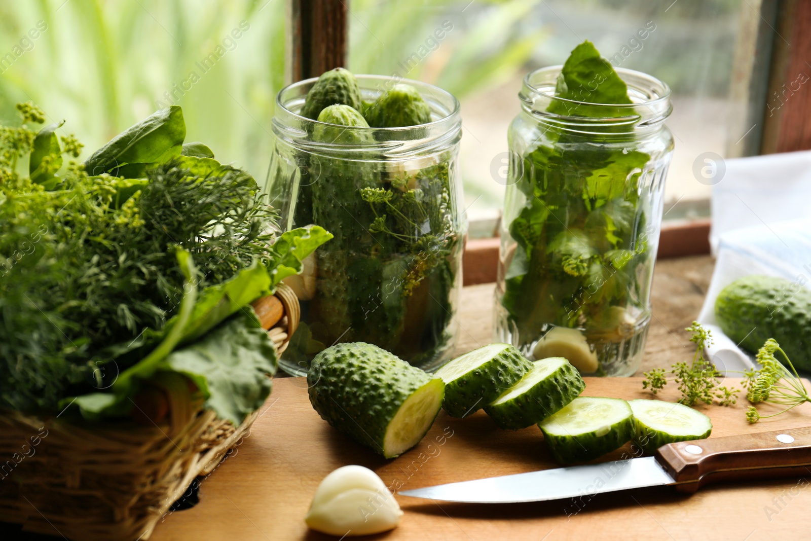 Photo of Glass jars, fresh vegetables and herbs on wooden table indoors. Pickling recipe