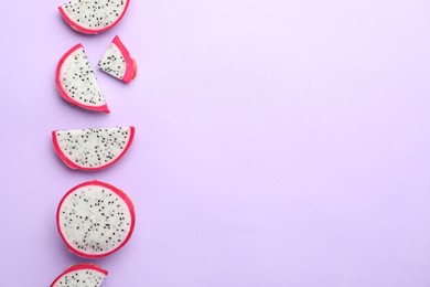 Photo of Slices of delicious dragon fruit (pitahaya) on violet background, flat lay. Space for text