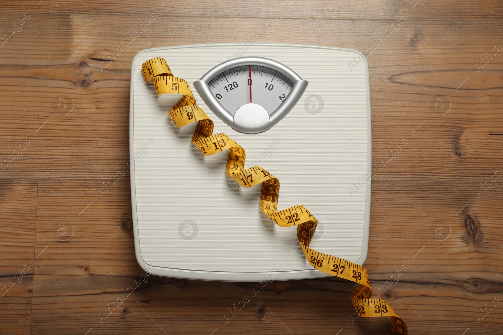 Photo of Scales and measuring tape on wooden floor, top view