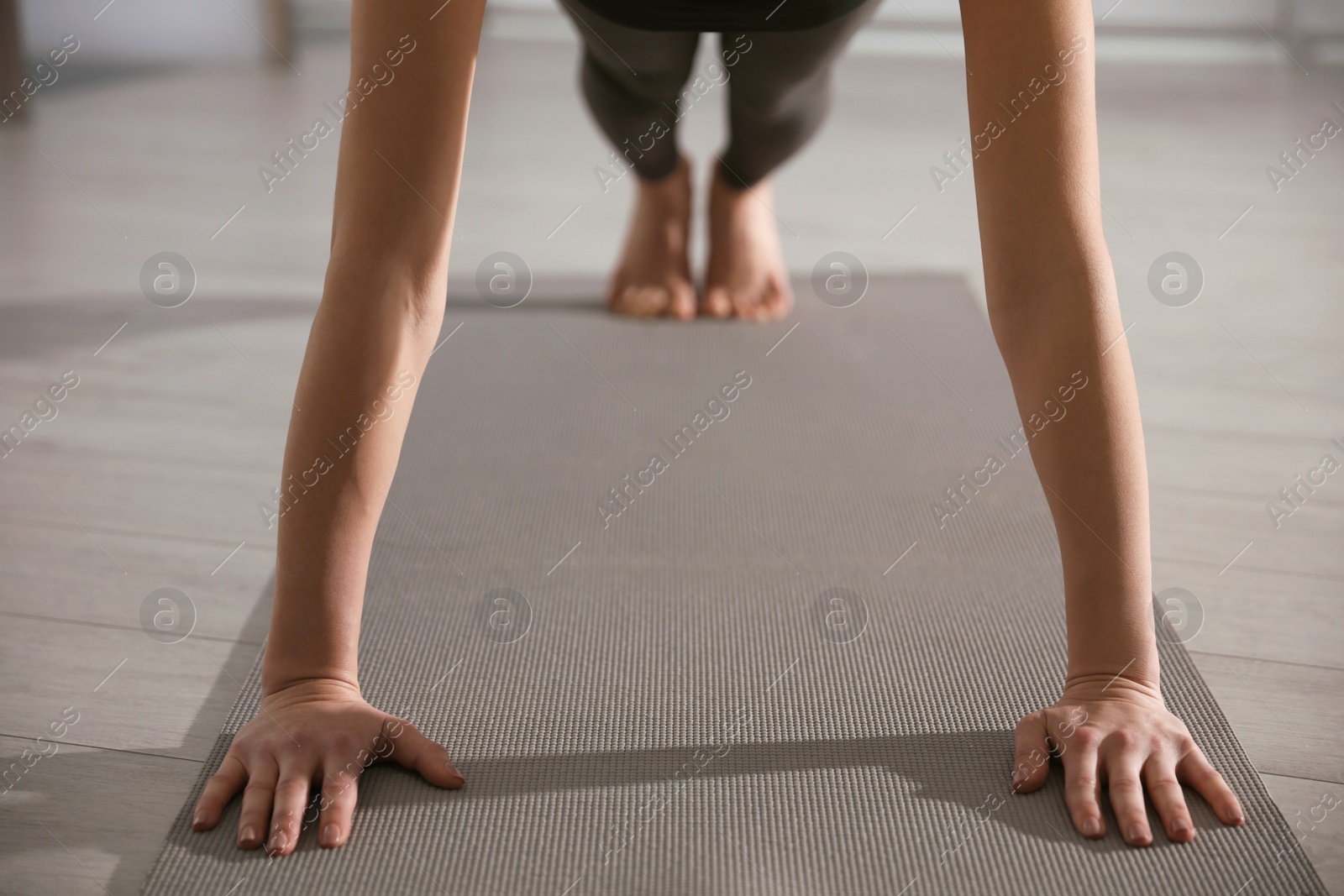 Photo of Young woman practicing plank asana in yoga studio, closeup. Phalankasana pose