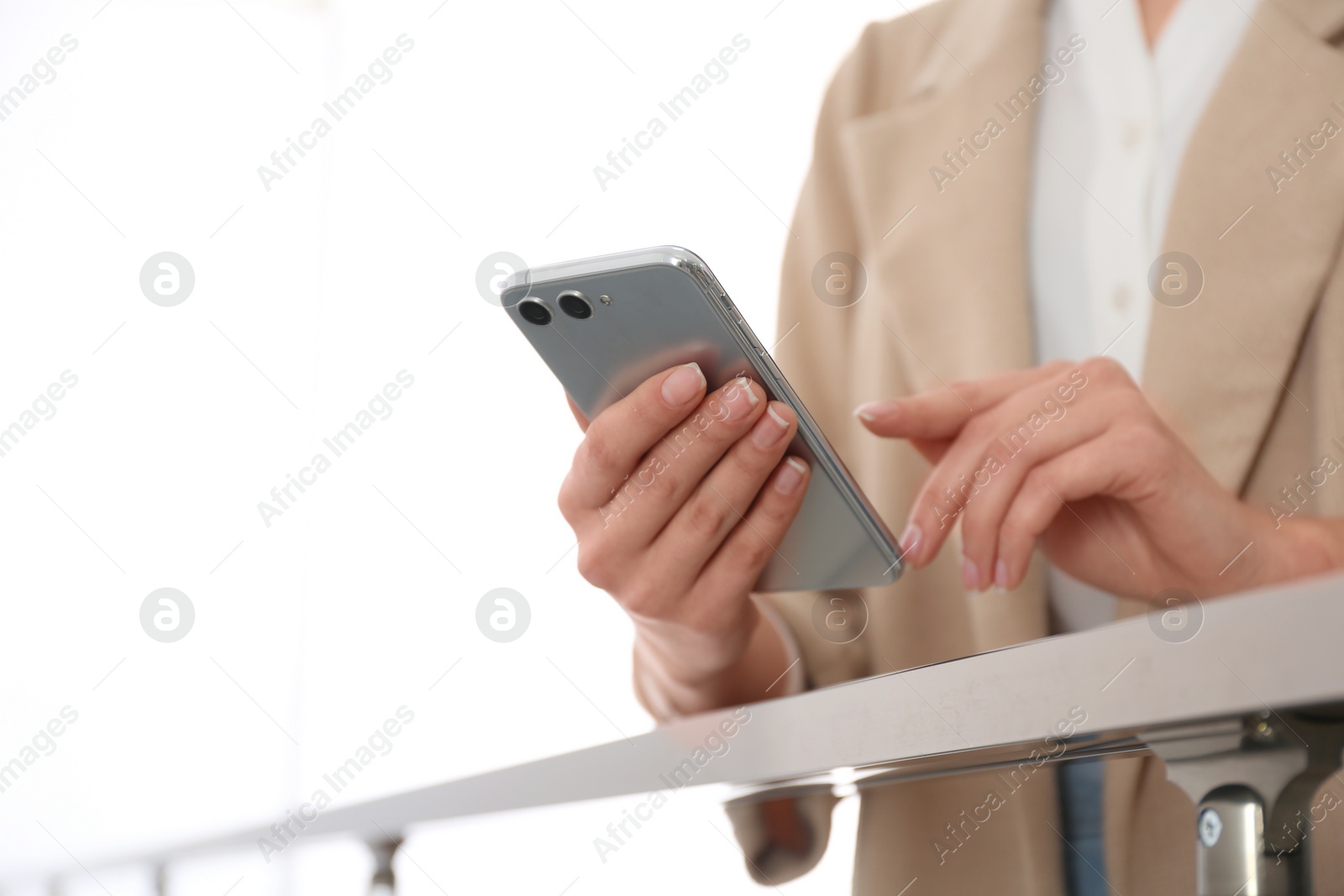 Photo of Young woman using modern smartphone indoors, closeup