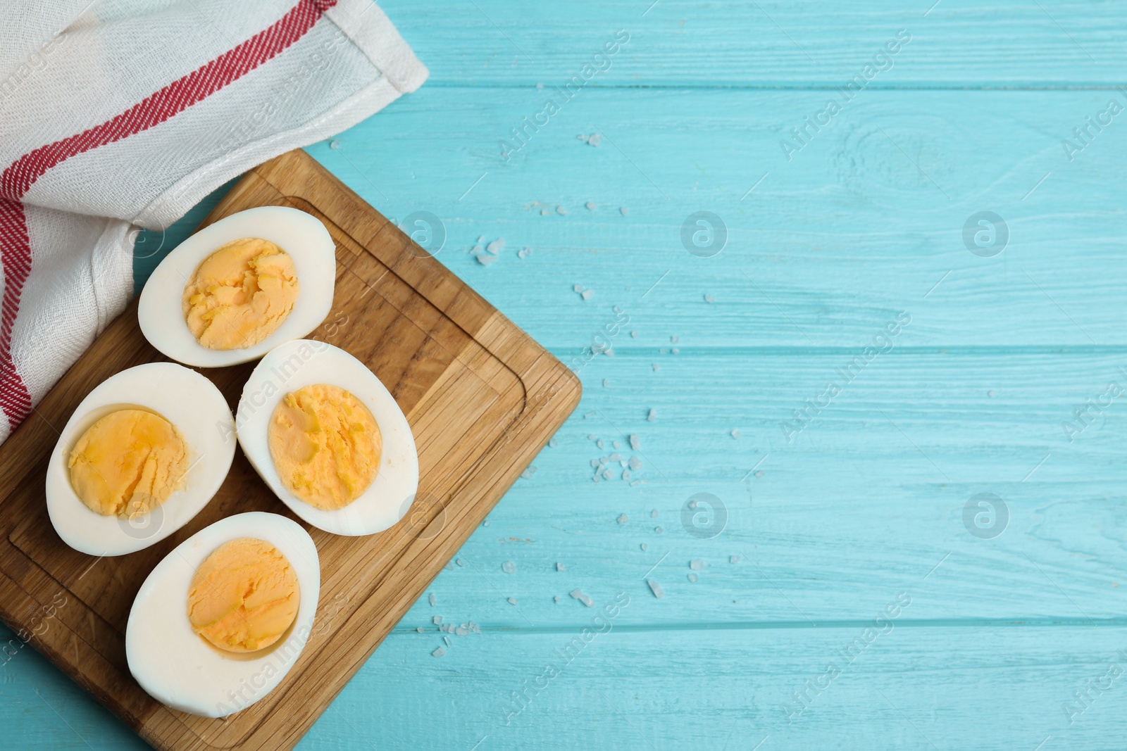 Photo of Cut hard boiled chicken eggs on light blue wooden table, flat lay. Space for text