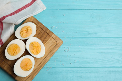 Photo of Cut hard boiled chicken eggs on light blue wooden table, flat lay. Space for text