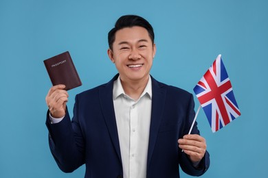 Photo of Immigration. Happy man with passport and flag of United Kingdom on light blue background
