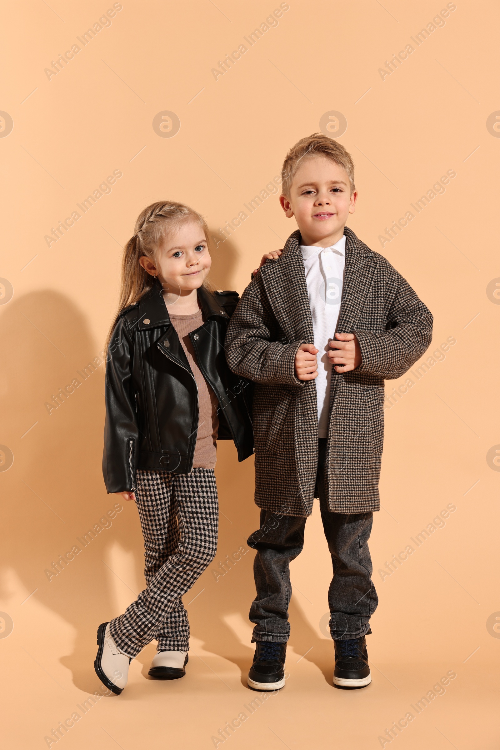 Photo of Fashion concept. Stylish children posing on pale orange background