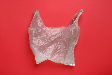 Photo of One plastic bag on red background, top view