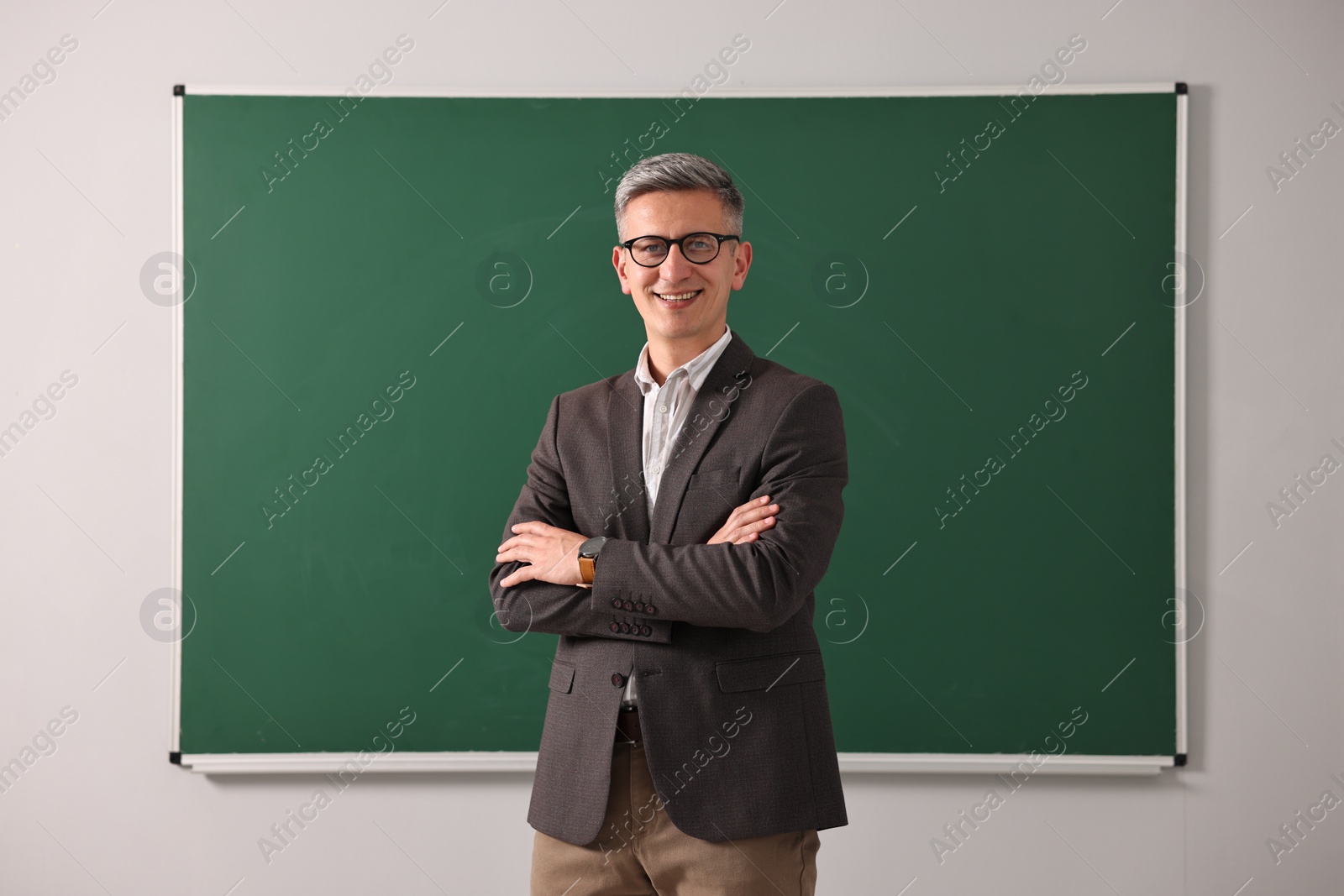 Photo of Teacher in glasses near chalkboard in classroom