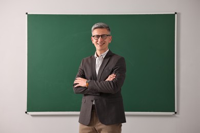 Teacher in glasses near chalkboard in classroom