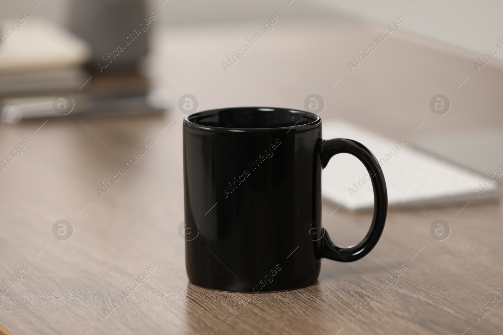 Photo of Black ceramic mug on wooden table at workplace