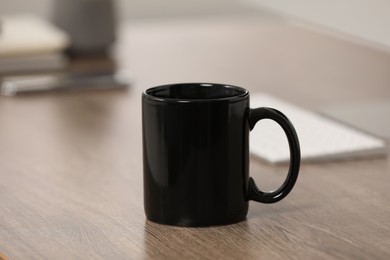 Photo of Black ceramic mug on wooden table at workplace