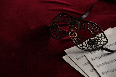 Elegant face mask and music sheets on red fabric, space for text. Theatrical performance