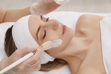 Photo of Young woman during face peeling procedure in salon