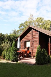 Photo of Cozy wooden house surrounded by lush nature on sunny day