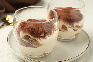 Delicious tiramisu in glasses on white table, closeup