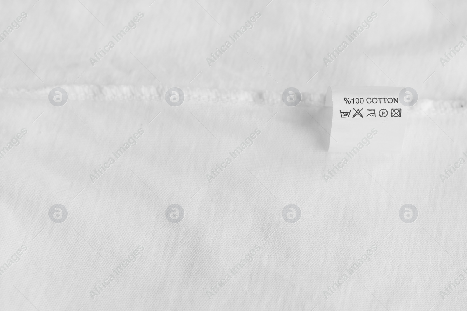 Photo of Clothing label with care information on white garment, space for text