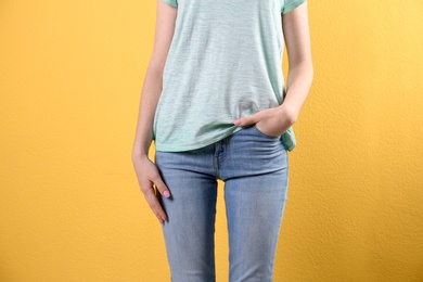 Photo of Young woman in stylish jeans on color background