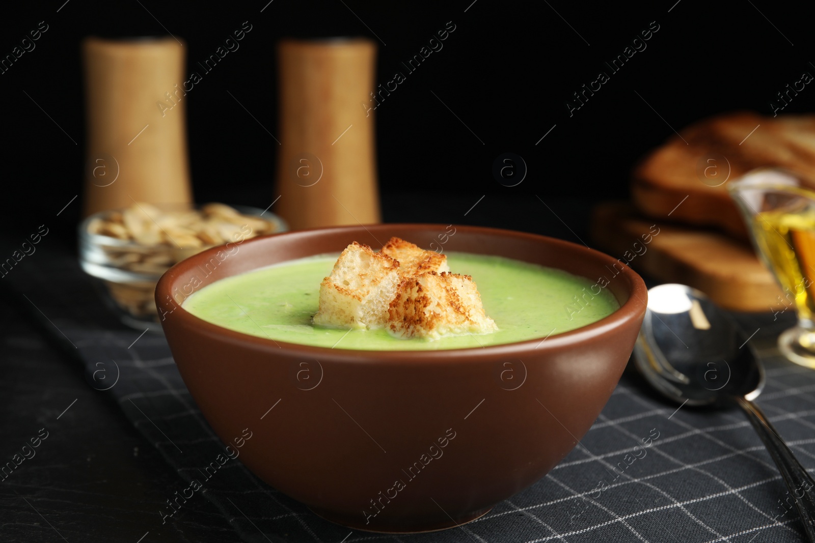 Photo of Delicious broccoli cream soup served on black table