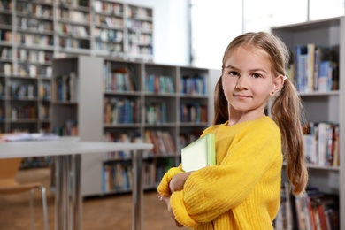 Cute little girl with books in library reading room