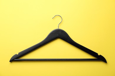 Photo of Black hanger on yellow background, top view
