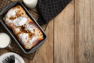 Delicious yeast dough cake in baking pan and milk on wooden table, flat lay. Space for text