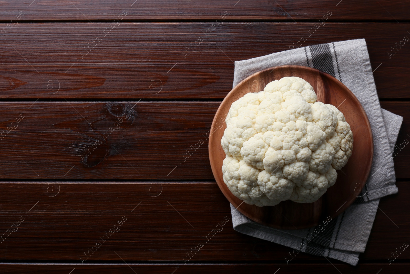 Photo of Plate with fresh raw cauliflower on wooden table, top view. Space for text