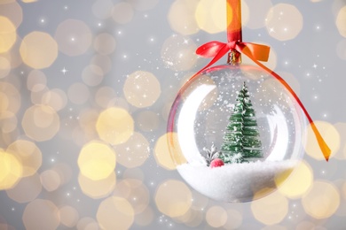 Image of Beautiful transparent Christmas ornament against blurred festive lights, bokeh effect. Space for text