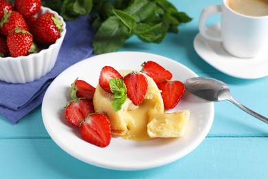 Photo of Tasty vanilla fondant with white chocolate and strawberries on light blue wooden table