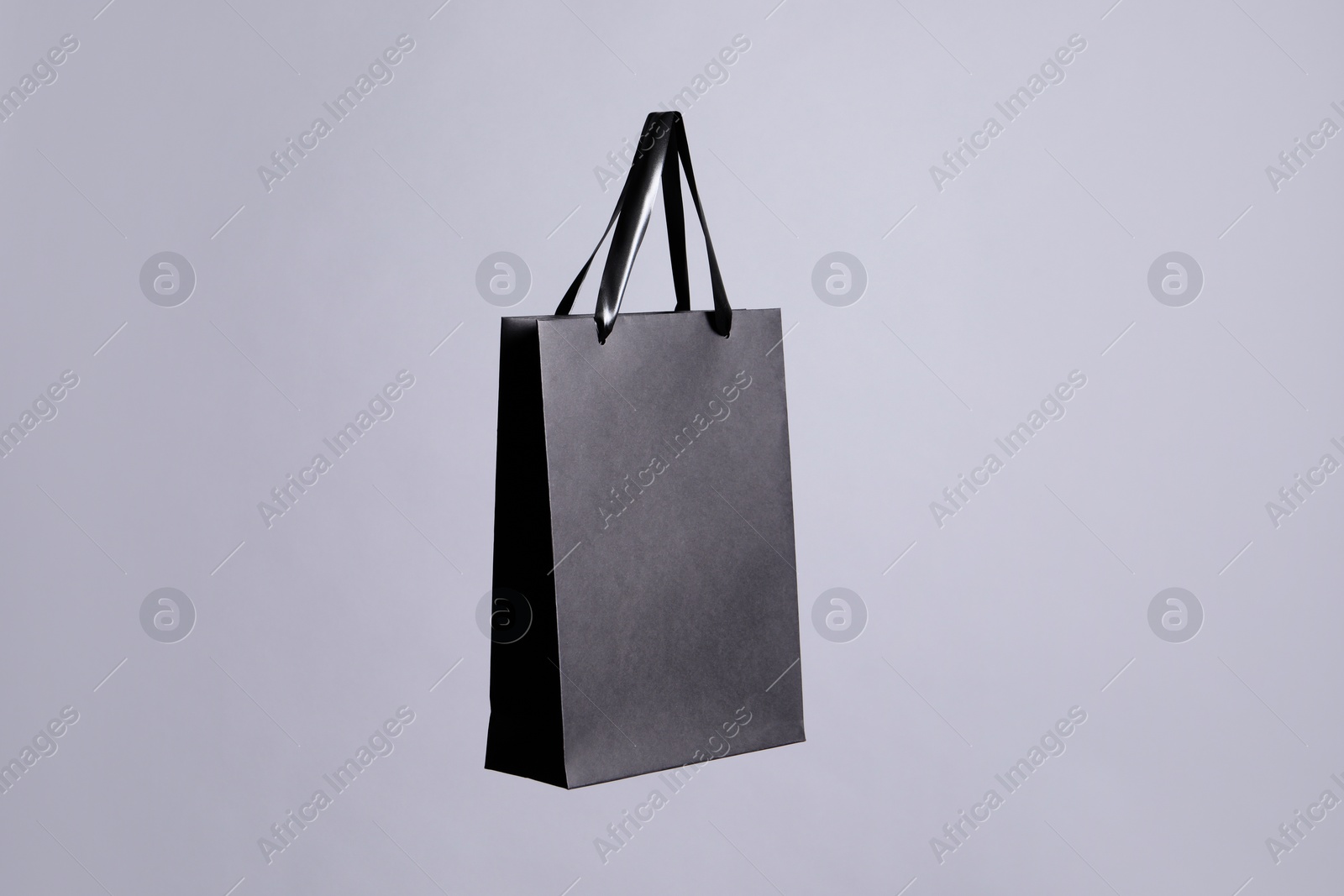 Photo of One black paper shopping bag on grey background. Space for text