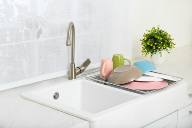 Photo of Drying rack with clean dishes over sink in kitchen