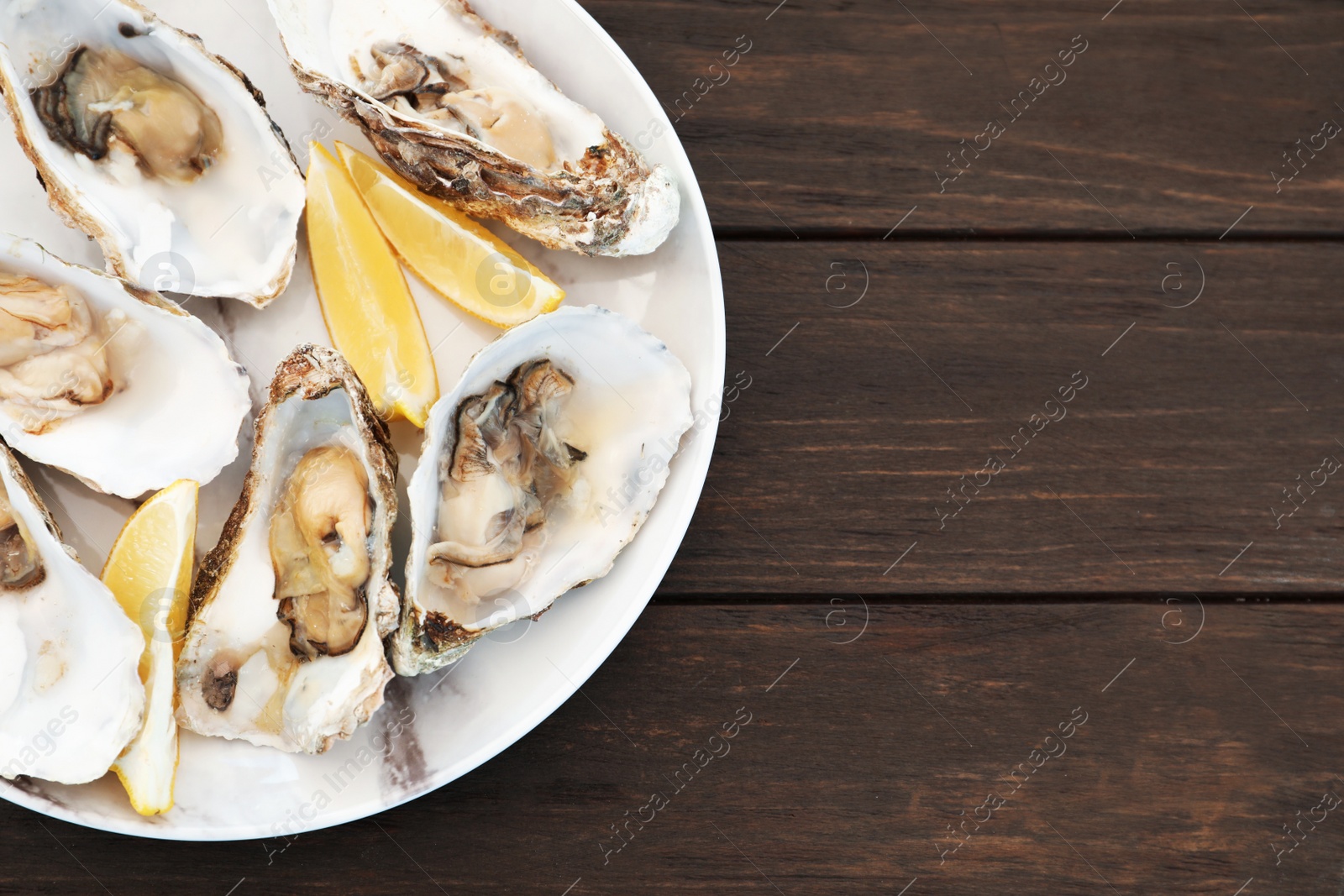 Photo of Fresh oysters with cut juicy lemon and space for text on table, top view