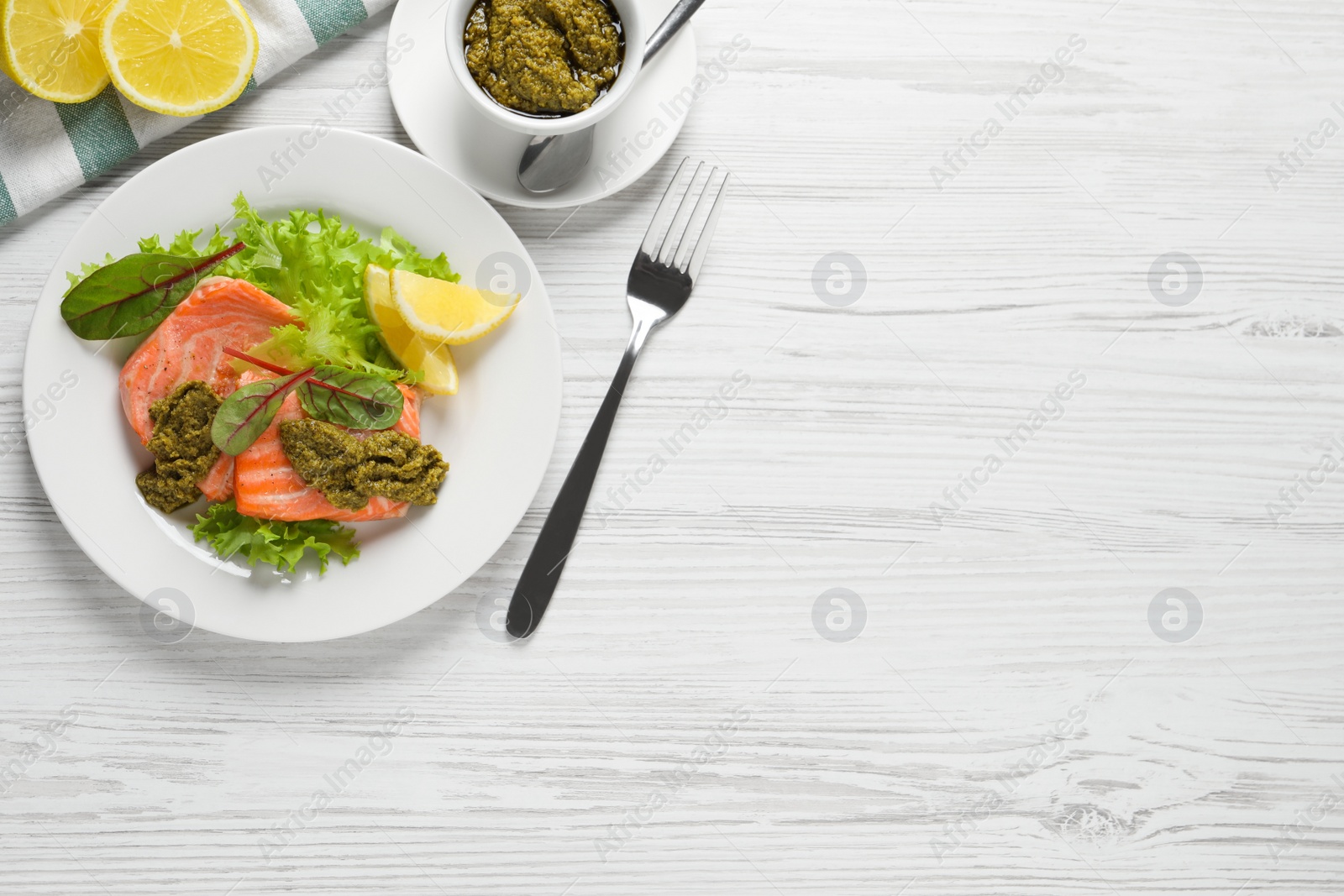 Photo of Tasty cooked salmon with pesto sauce on white wooden table, flat lay. Space for text