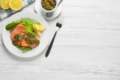 Photo of Tasty cooked salmon with pesto sauce on white wooden table, flat lay. Space for text