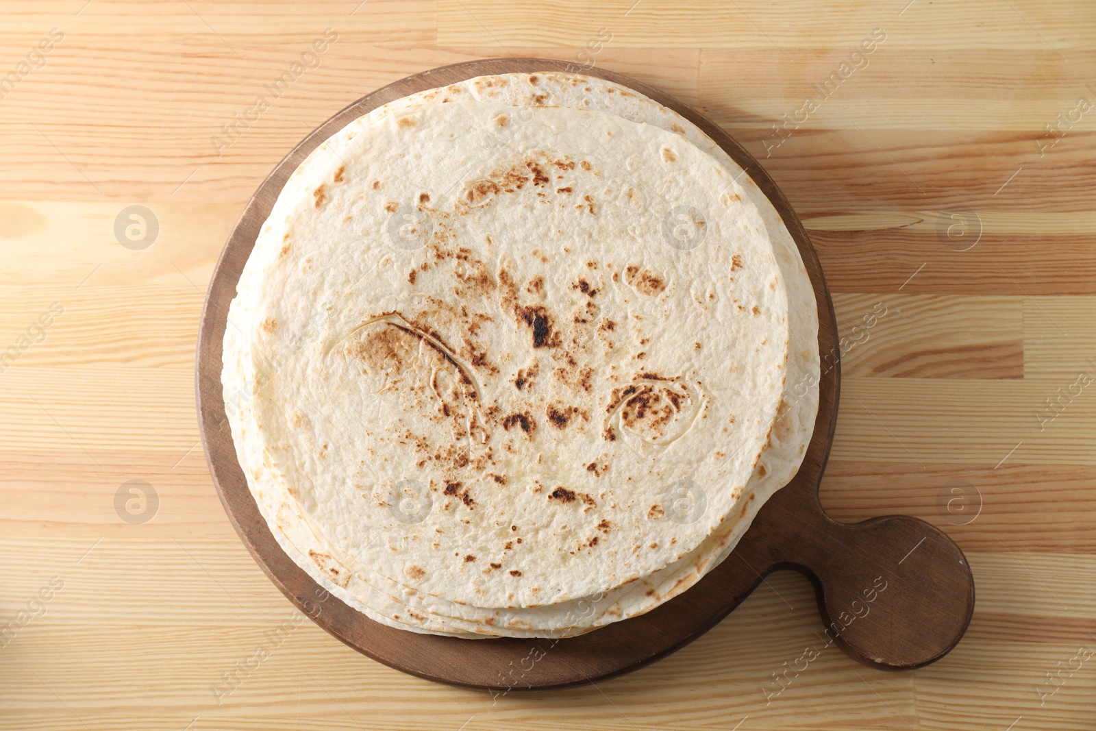 Photo of Many tasty homemade tortillas on wooden table, top view