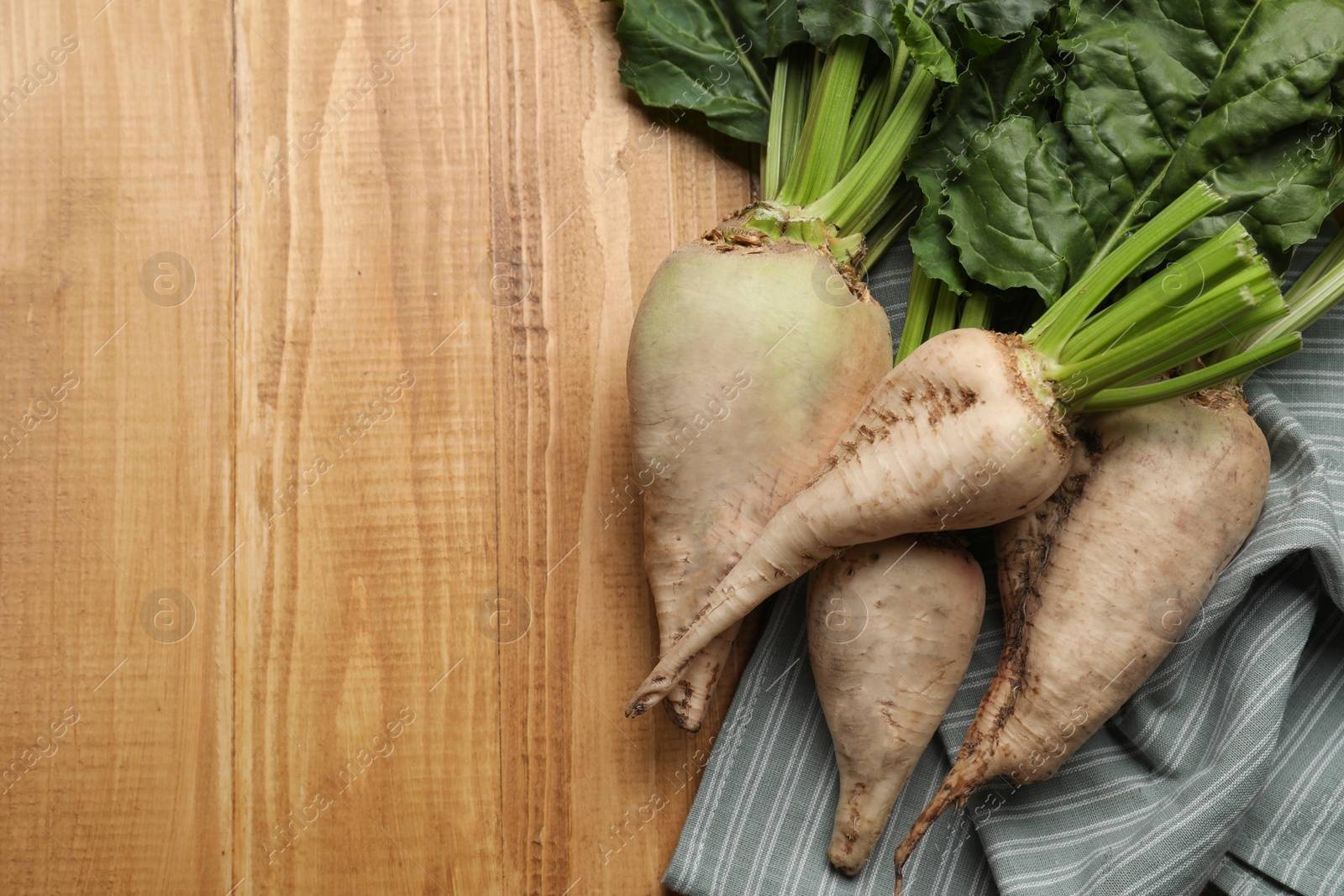 Photo of Fresh sugar beets with leaves on wooden table, flat lay. Space for text