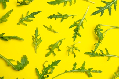 Fresh arugula on yellow background, flat lay