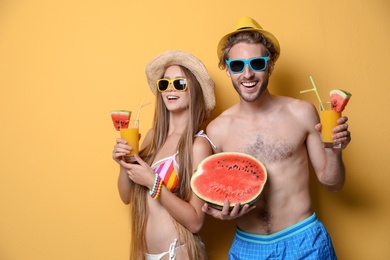 Young couple in beachwear with cocktails on color background