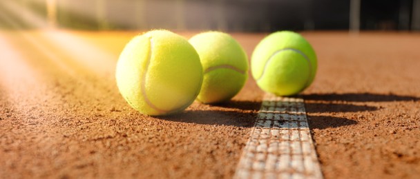 Image of Bright yellow tennis balls on clay court, banner design