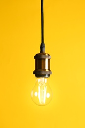 Photo of Hanging modern lamp bulb against yellow background