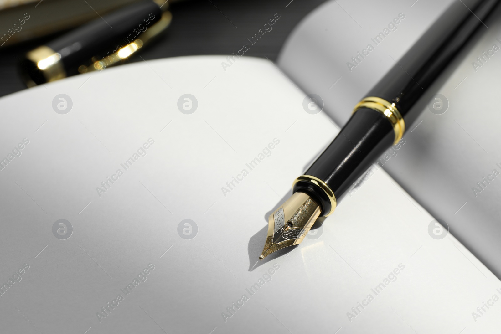 Photo of Stylish black fountain pen on open notebook, closeup. Space for text