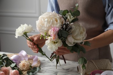 Photo of Florist creating beautiful bouquet at white marble table, closeup