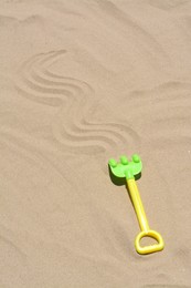 Plastic rake on sand, space for text. Beach toy