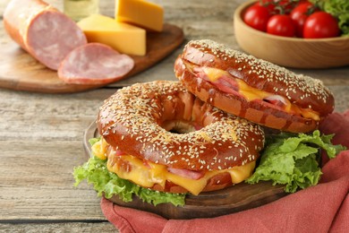 Photo of Delicious bagels with ham and cheese on wooden table