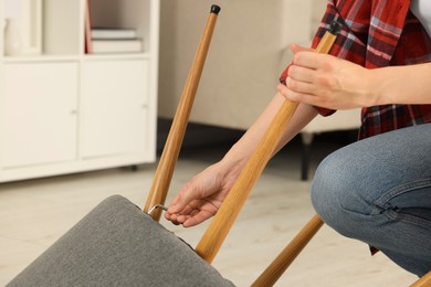 Photo of Woman with hex key assembling armchair indoors, closeup