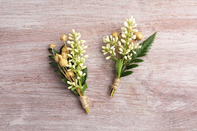 Photo of Small stylish boutonnieres on light wooden table, top view
