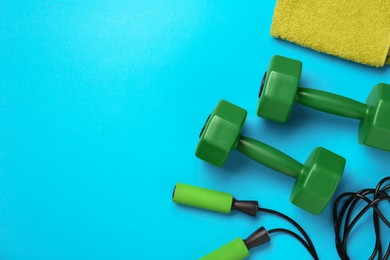 Flat lay composition with dumbbells on light blue background, space for text