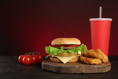 Photo of Delicious fast food menu on black table against red background
