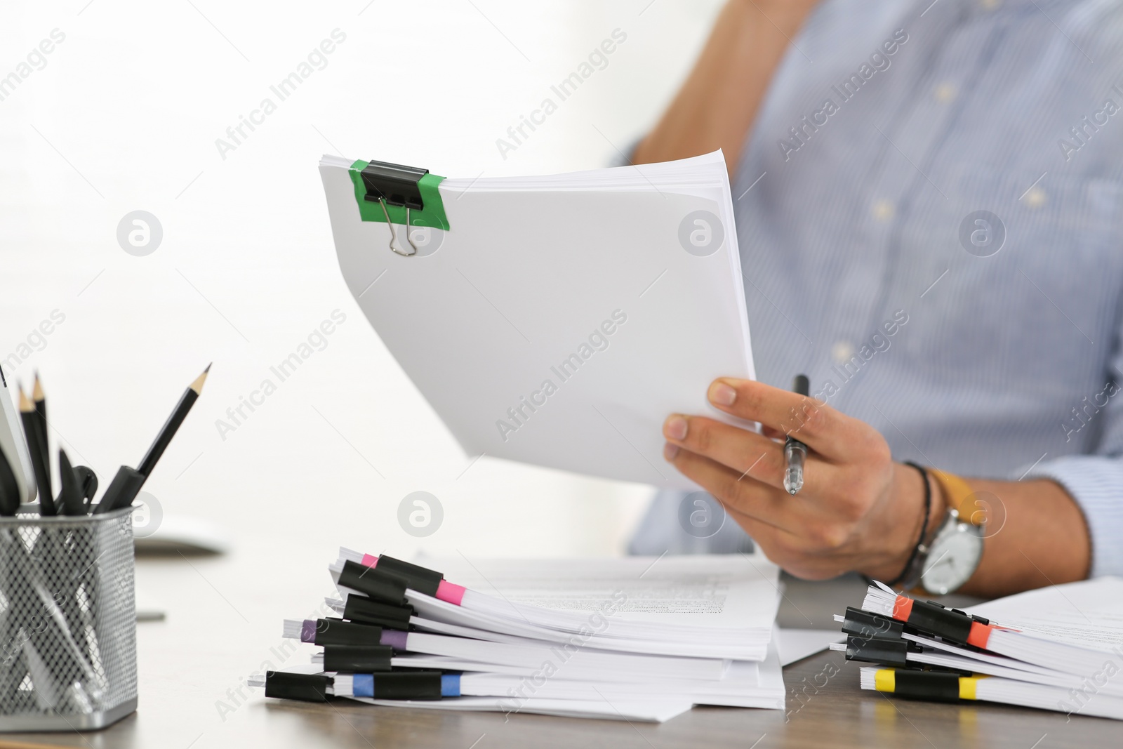 Photo of Man working with documents at wooden table in office, closeup