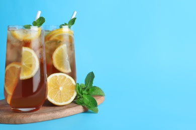 Photo of Delicious iced tea with lemon and mint on light blue background. Space for text