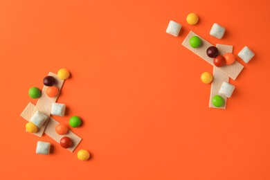 Different tasty chewing gums on orange background, flat lay. Space for text