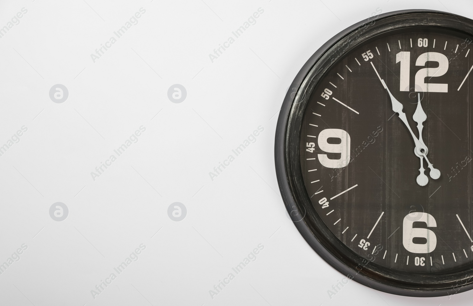 Photo of Stylish analog clock hanging on white wall, space for text. New Year countdown